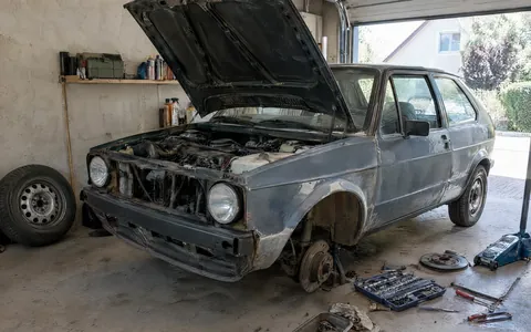 Bastlerfahrzeug mit geöffneter Motorhaube in einer Garage